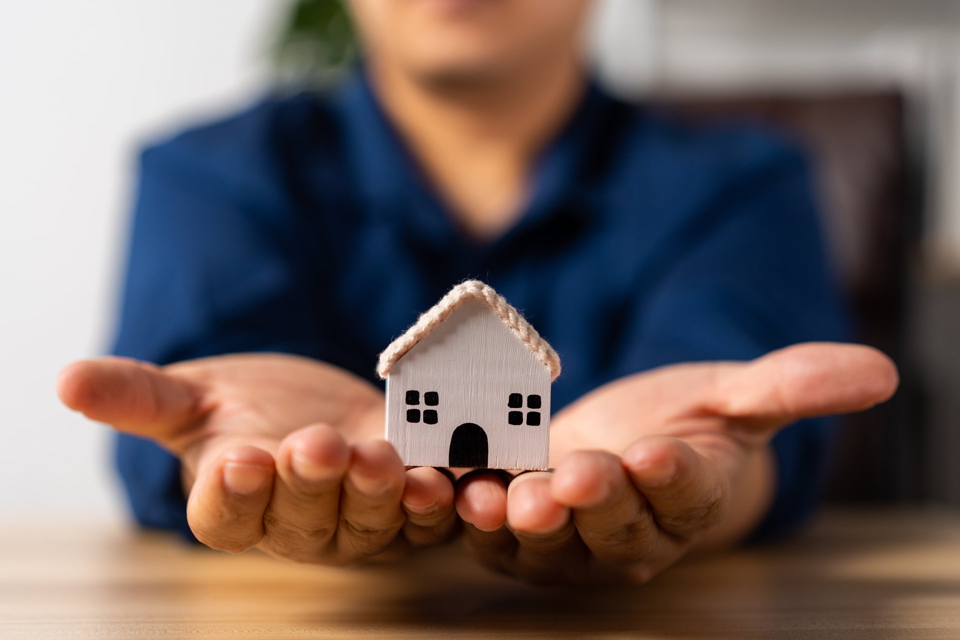 Agent nieruchomości trzymający model białego domu na dłoni, koncepcja hipoteki na nieruchomości, pożyczki mieszkaniowej, ubezpieczenia domu, nieruchomości